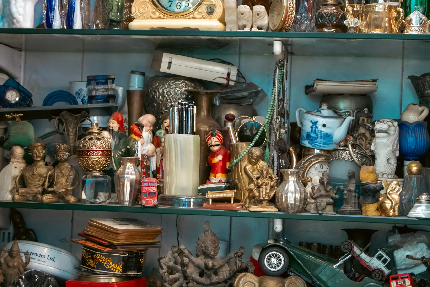 Regal voller Figuren, Teekanne, Spielzeugautos und Messing
