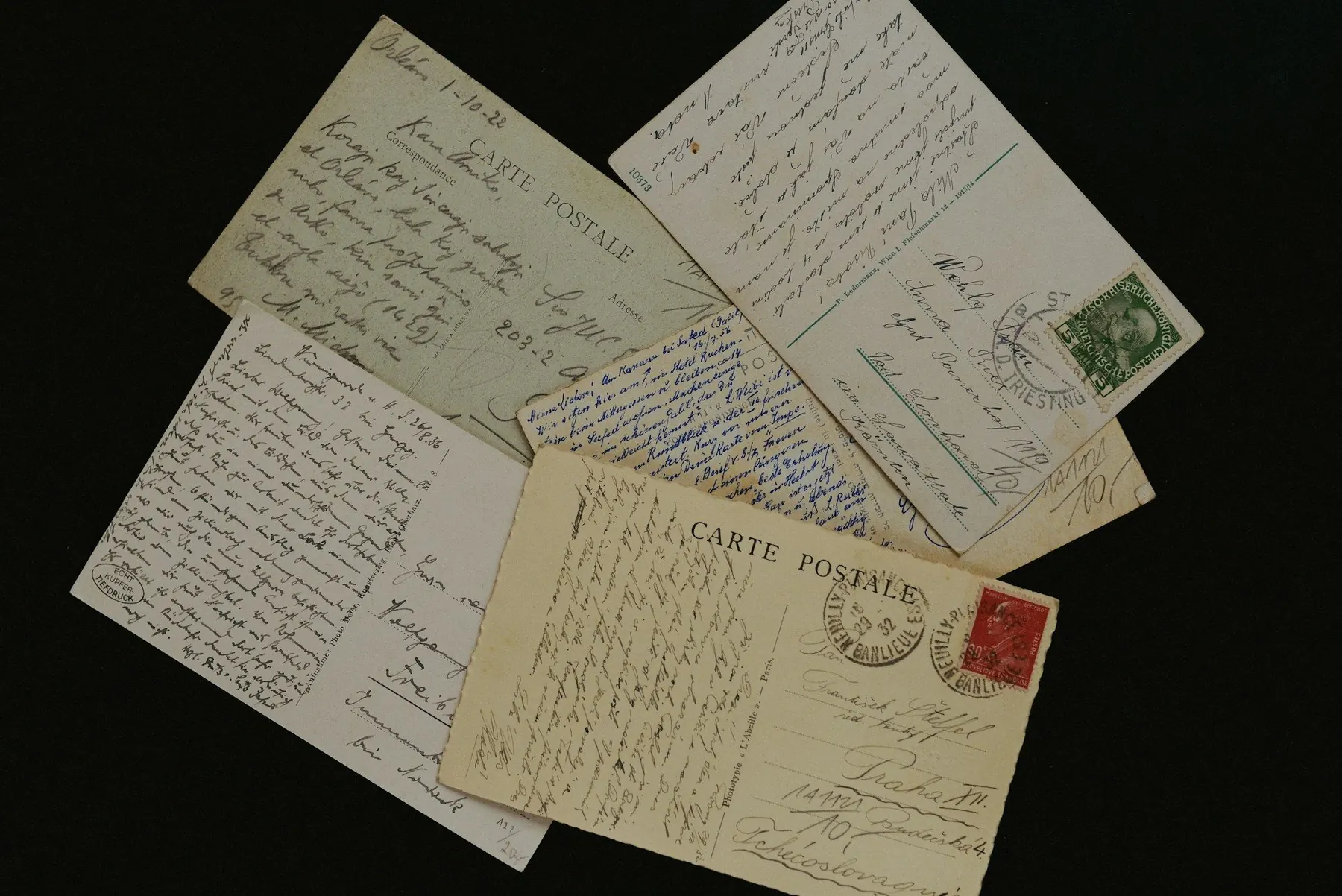 Handbeschriebene Postkarten mit Briefmarken auf schwarzem Grund