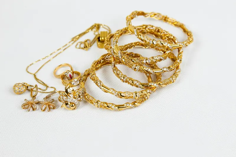 Goldene Armreifen, Ketten und Ringe auf weißem Grund