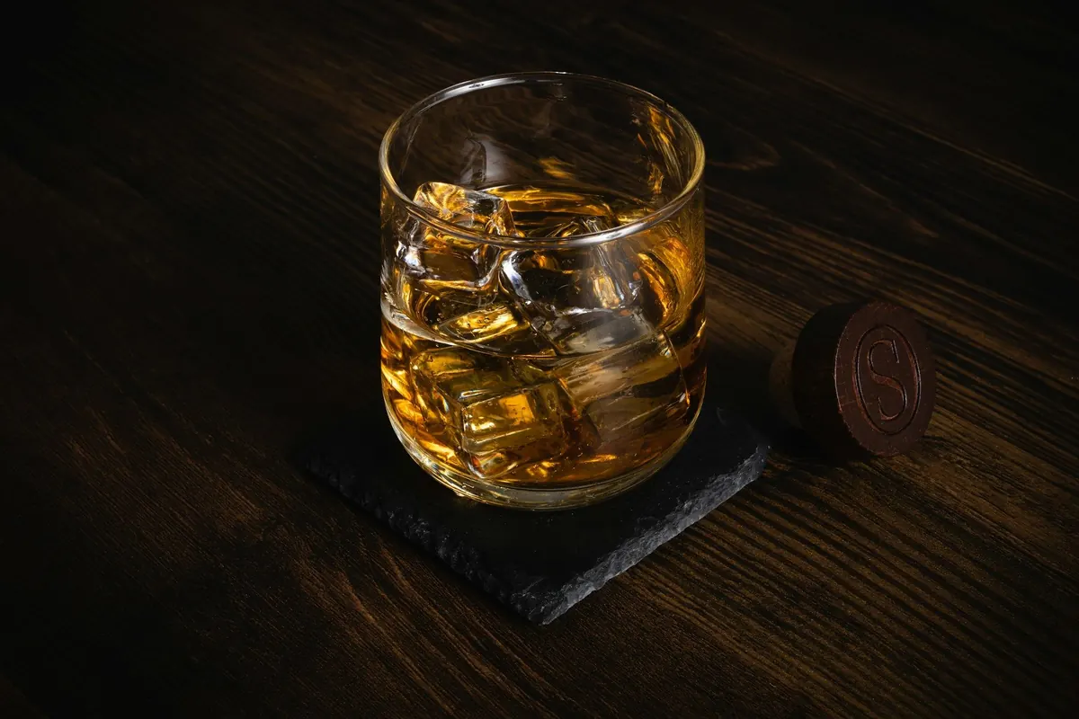 Whiskyglas mit Eis auf Schieferuntersetzer
