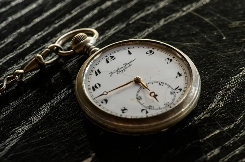 Taschenuhr mit Kette auf dunklem Holz